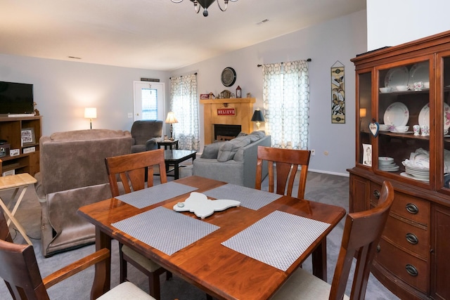 carpeted dining space with an inviting chandelier