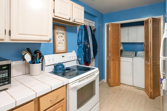 kitchen featuring white range with electric stovetop, tile countertops, white cabinets, and washer and dryer