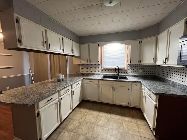 kitchen featuring white cabinetry, kitchen peninsula, decorative backsplash, and sink