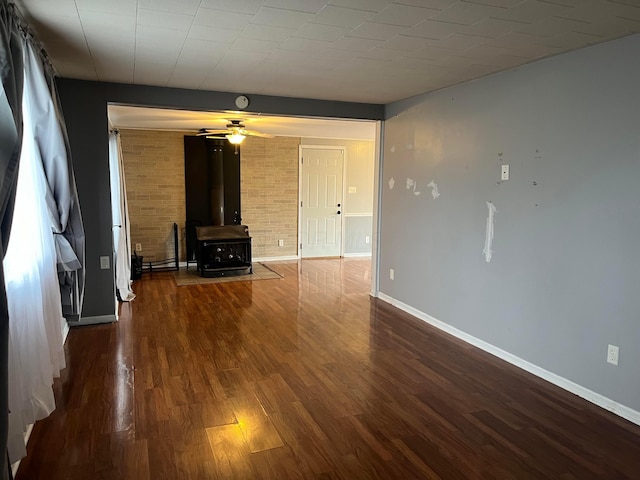 unfurnished living room featuring dark hardwood / wood-style floors, ceiling fan, and a wood stove