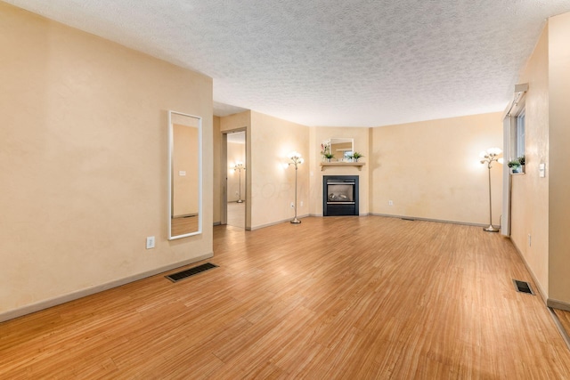 unfurnished living room featuring light hardwood / wood-style floors and a textured ceiling