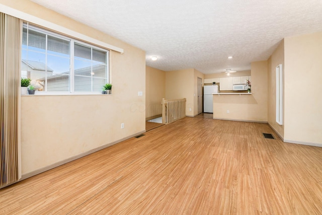 unfurnished living room with light hardwood / wood-style floors and a textured ceiling