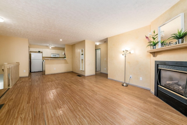 unfurnished living room featuring a textured ceiling, light wood-type flooring, and radiator heating unit