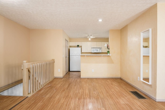 interior space featuring a textured ceiling and light hardwood / wood-style flooring