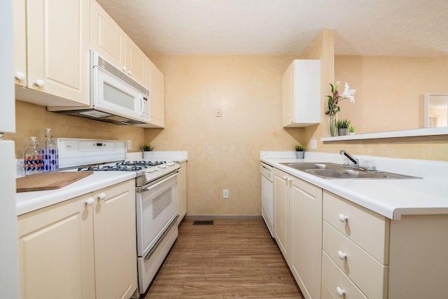 kitchen featuring a textured ceiling, white appliances, sink, light hardwood / wood-style flooring, and white cabinets