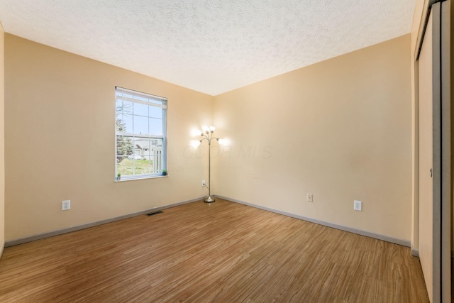 unfurnished room featuring hardwood / wood-style floors and a textured ceiling