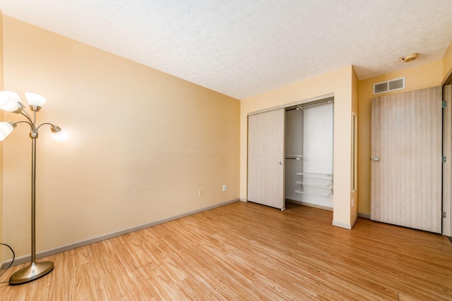 unfurnished bedroom with a closet, wood-type flooring, and a textured ceiling