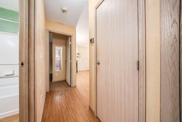 corridor featuring light hardwood / wood-style floors and a textured ceiling