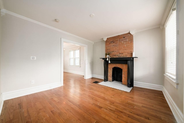 unfurnished living room featuring a brick fireplace, crown molding, and hardwood / wood-style flooring