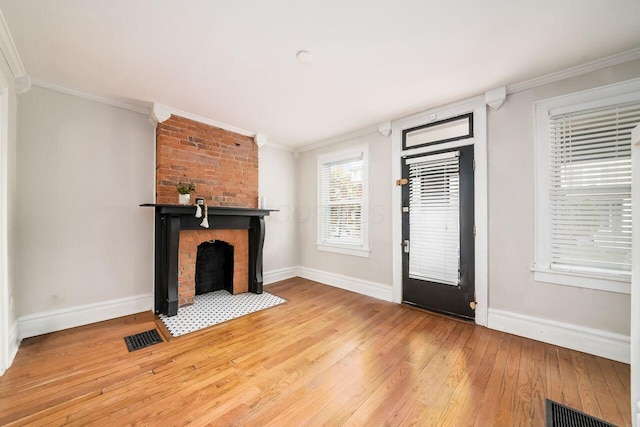 unfurnished living room with ornamental molding, wood-type flooring, and a brick fireplace