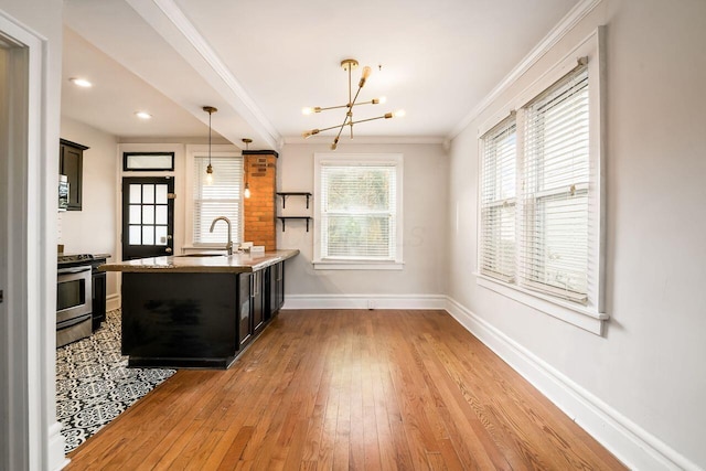 kitchen with sink, light wood-type flooring, decorative light fixtures, stainless steel range oven, and kitchen peninsula