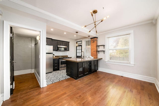 kitchen featuring ornamental molding, stainless steel appliances, sink, decorative light fixtures, and light hardwood / wood-style flooring