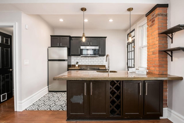 kitchen featuring light stone countertops, stainless steel appliances, sink, dark hardwood / wood-style floors, and hanging light fixtures