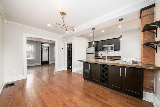 kitchen with stainless steel appliances, crown molding, decorative light fixtures, decorative backsplash, and hardwood / wood-style flooring