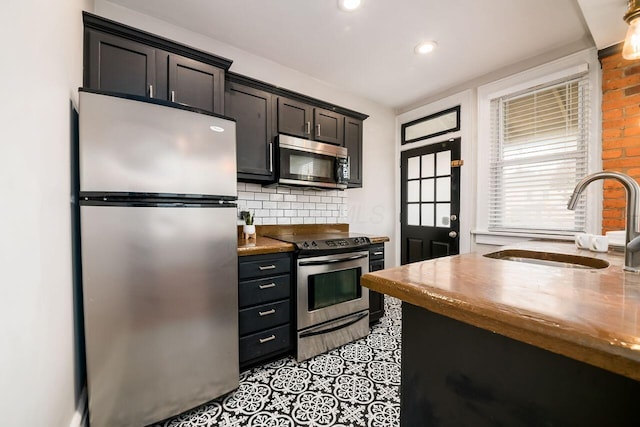 kitchen with butcher block counters, decorative backsplash, sink, and appliances with stainless steel finishes