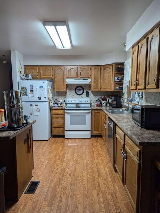 kitchen featuring backsplash, sink, light hardwood / wood-style floors, and white appliances