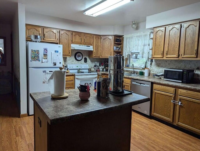 kitchen featuring light wood-type flooring, tasteful backsplash, stainless steel appliances, sink, and a center island