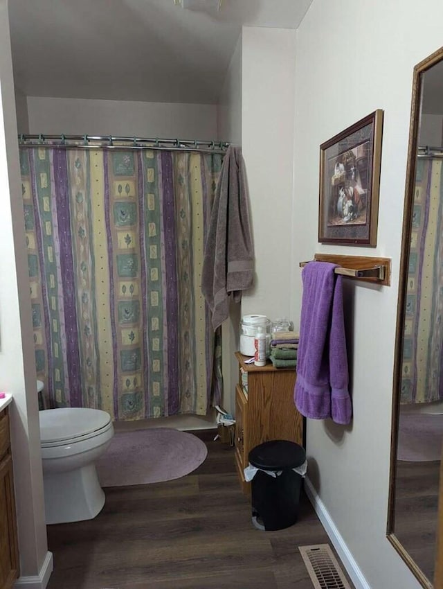 bathroom with hardwood / wood-style floors, vanity, toilet, and curtained shower