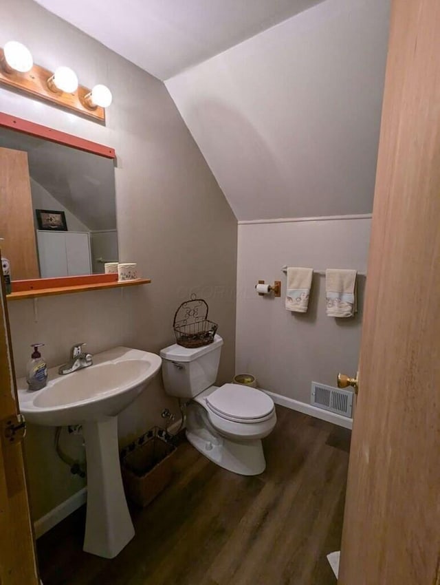 bathroom featuring toilet, wood-type flooring, and vaulted ceiling