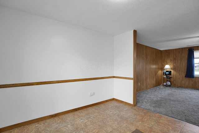 empty room with wood walls and a textured ceiling