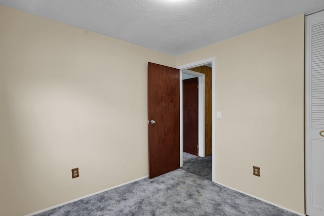 unfurnished bedroom featuring a textured ceiling, light colored carpet, and a closet