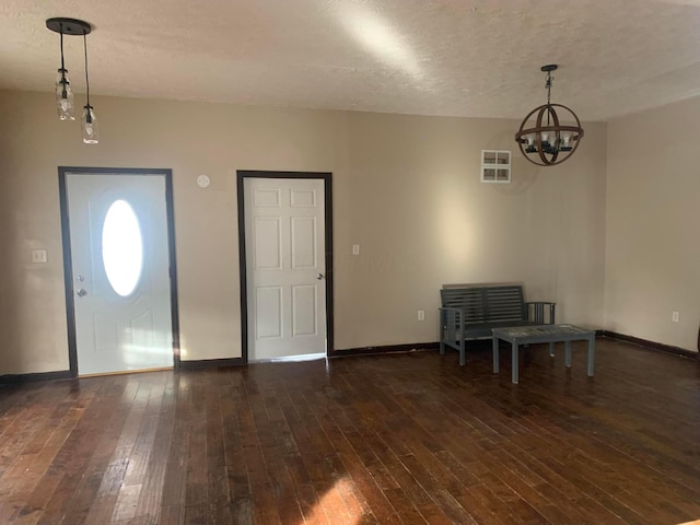 foyer featuring a chandelier, dark wood-type flooring, and a textured ceiling