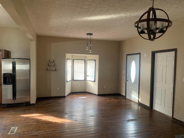 foyer entrance with a textured ceiling, an inviting chandelier, and dark wood-type flooring