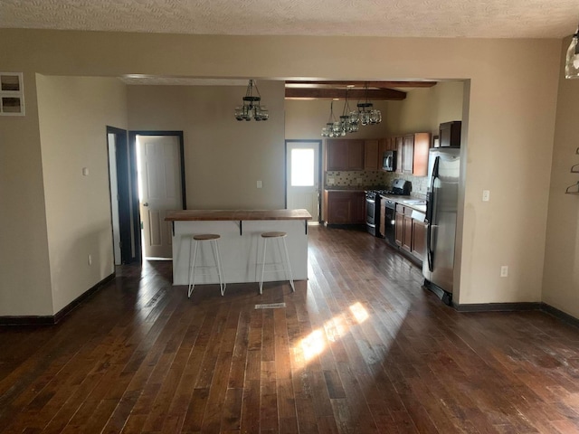 kitchen featuring a breakfast bar area, stainless steel appliances, dark hardwood / wood-style floors, and an inviting chandelier