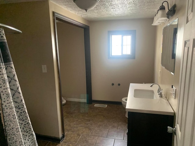 bathroom featuring tile patterned flooring, vanity, toilet, and a textured ceiling