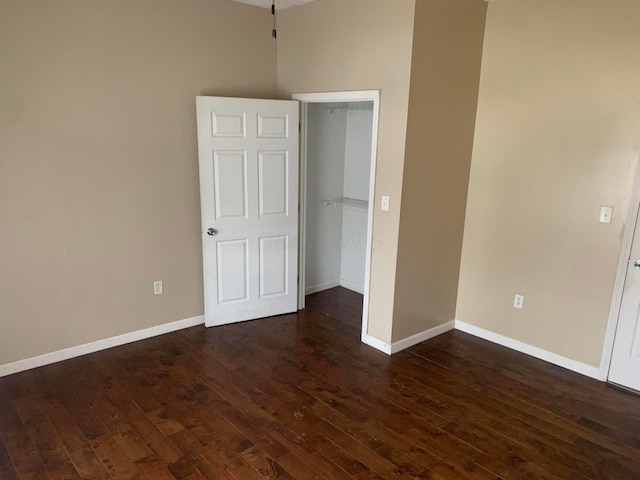 unfurnished bedroom with dark wood-type flooring and a closet