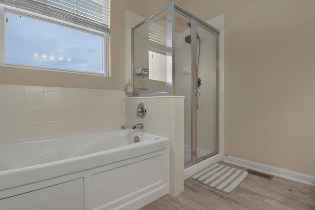 bathroom featuring plus walk in shower and wood-type flooring