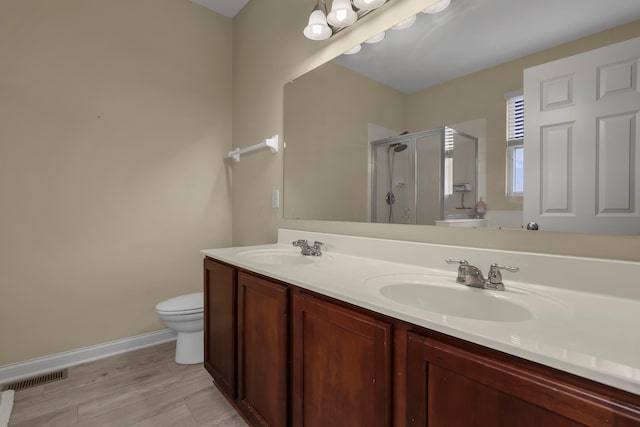 bathroom with wood-type flooring, vanity, toilet, and a shower with door