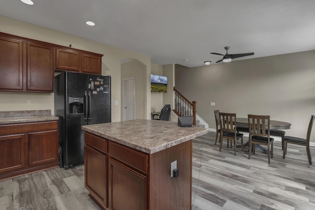 kitchen featuring black fridge with ice dispenser, a center island, light hardwood / wood-style floors, and ceiling fan