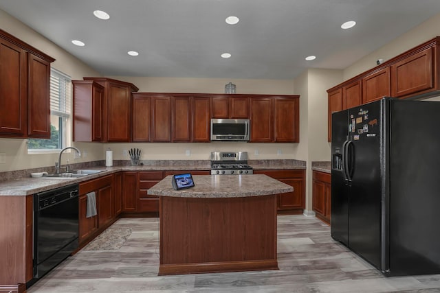 kitchen featuring sink, light hardwood / wood-style flooring, a kitchen island, and black appliances