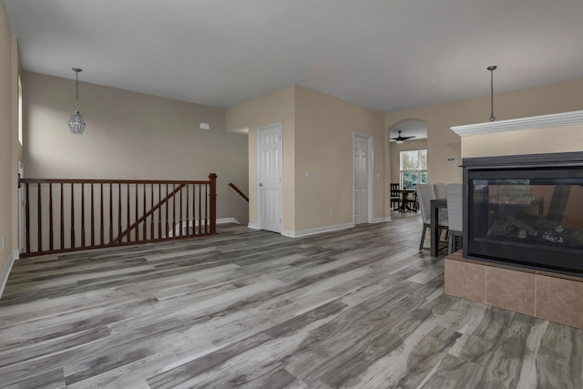 unfurnished living room featuring hardwood / wood-style floors, ceiling fan, and a multi sided fireplace