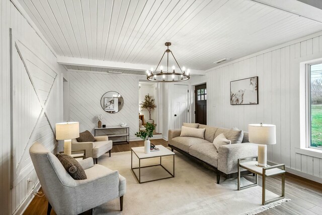 living room with a notable chandelier, light hardwood / wood-style floors, wood ceiling, and beam ceiling