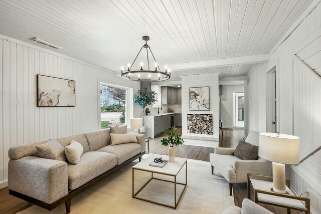 living room with beam ceiling, sink, light hardwood / wood-style flooring, a notable chandelier, and wood ceiling