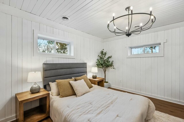 bedroom featuring dark hardwood / wood-style floors, multiple windows, and wood walls