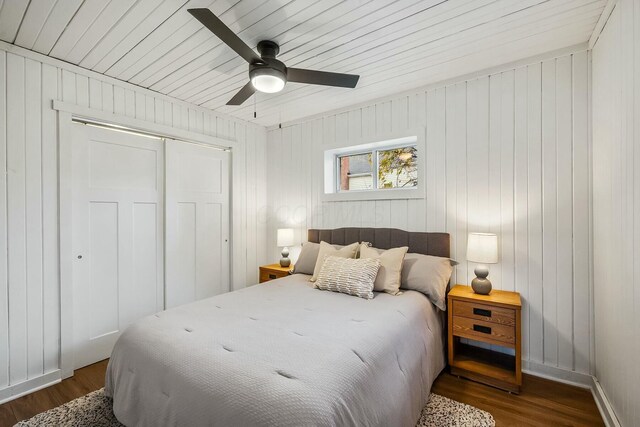 bedroom featuring wood walls, ceiling fan, dark hardwood / wood-style floors, and a closet