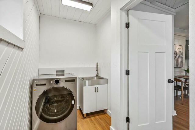 laundry area with cabinets, light hardwood / wood-style floors, washer / dryer, and sink