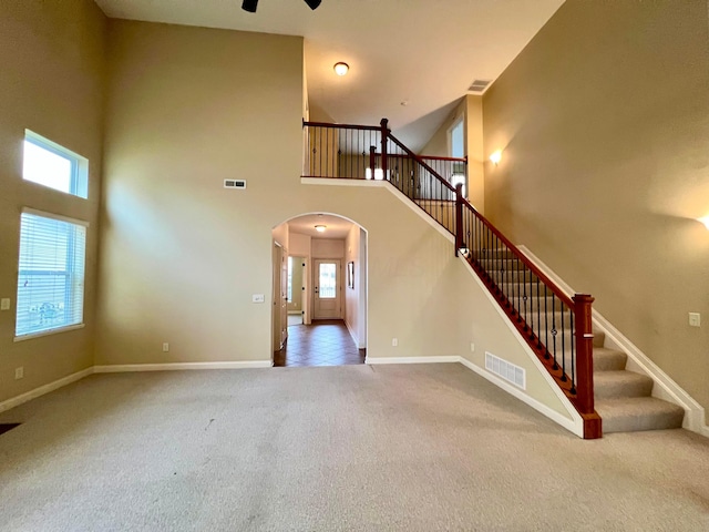 stairs with a wealth of natural light, carpet floors, and a towering ceiling