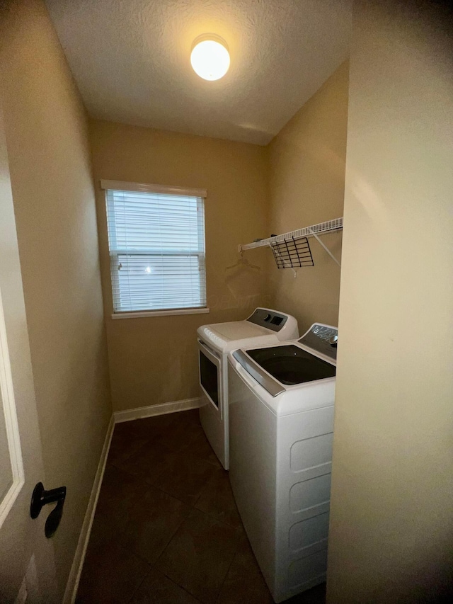 washroom with dark tile patterned floors, separate washer and dryer, and a textured ceiling