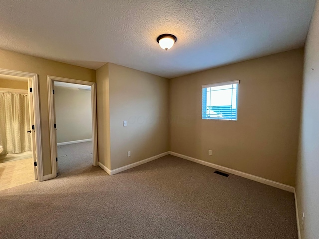 spare room featuring a textured ceiling and carpet