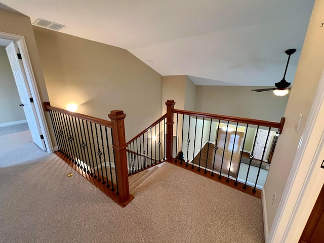 stairway featuring lofted ceiling, ceiling fan, and carpet