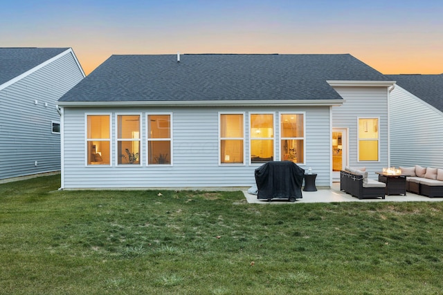 back house at dusk featuring a yard, an outdoor living space, and a patio area