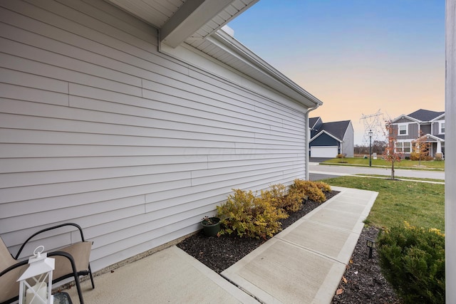 property exterior at dusk featuring a lawn