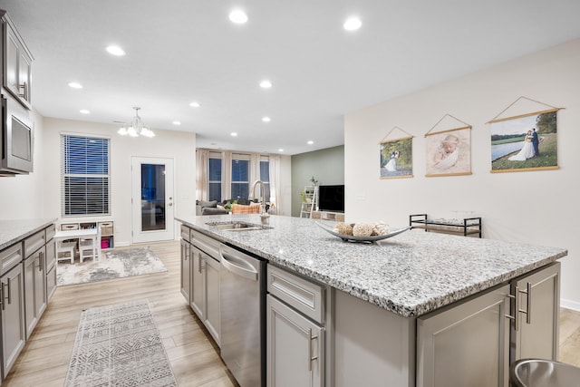 kitchen featuring gray cabinetry, sink, light hardwood / wood-style floors, a center island with sink, and appliances with stainless steel finishes