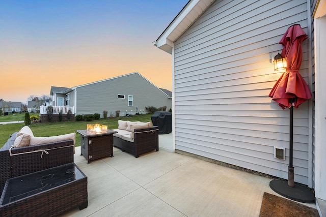 patio terrace at dusk featuring a yard and an outdoor living space with a fire pit