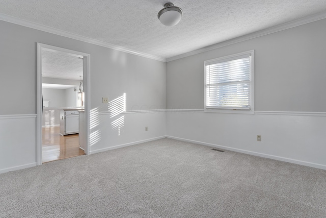 carpeted spare room with an inviting chandelier, a textured ceiling, and ornamental molding