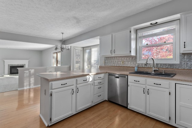 kitchen featuring dishwasher, plenty of natural light, kitchen peninsula, and decorative light fixtures